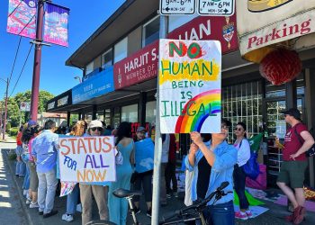 Protestors holding a sign that says, "No human being is illegal."
