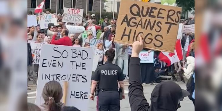 Protestors hold signs against anti- 2SLGBTQ+ Legislation.