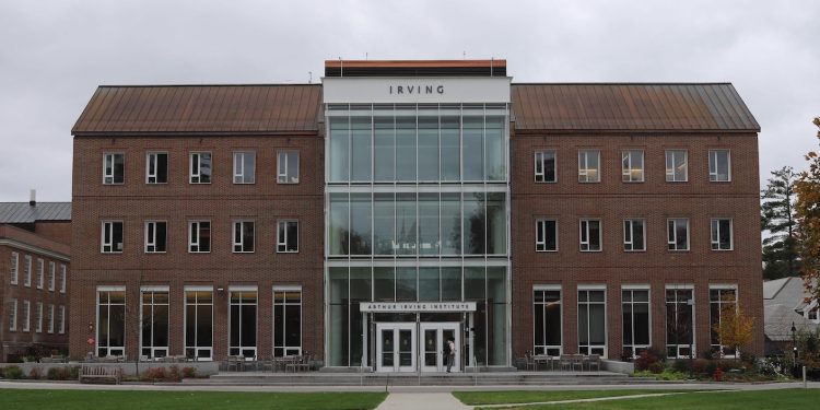An imposing brick building about four storeys high with what appears to be a central glass atrium and the name Irving written on the facade is pictured on a college campus.